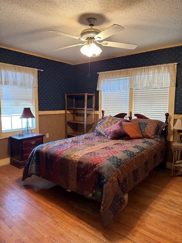 711 24th St, Crane, TX 79731 - bedroom featuring hardwood / wood-style floors, a textured ceiling, wallpapered walls, and a ceiling fan