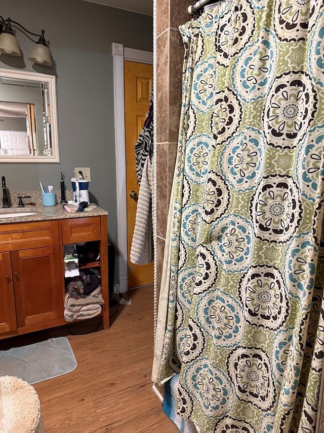 711 24th St, Crane, TX 79731 - bathroom with wood finished floors, vanity, and a shower with shower curtain