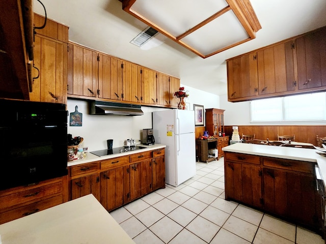 2104 Redbud Ave, Odessa, TX 79761 - kitchen with black appliances, under cabinet range hood, light countertops, light tile patterned floors, and brown cabinets