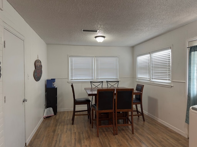 dining room with visible vents, baseboards, a textured ceiling, and wood finished floors