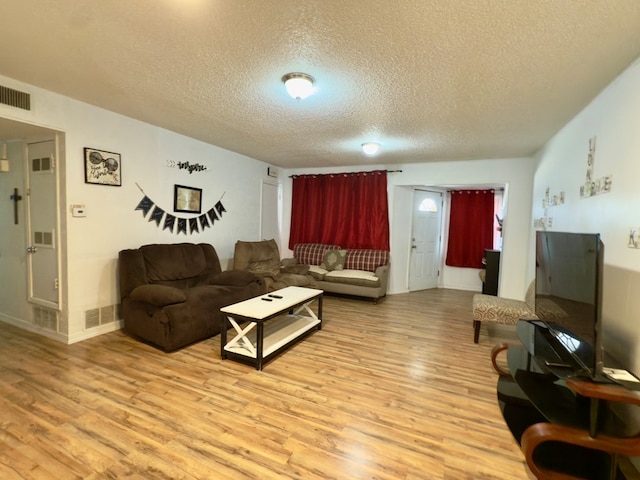 living area with light wood-style floors, visible vents, and a textured ceiling