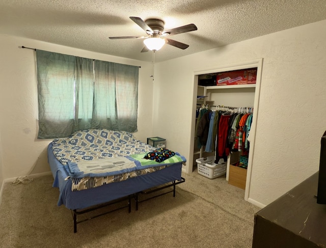 carpeted bedroom featuring a ceiling fan, a textured wall, a closet, and a textured ceiling