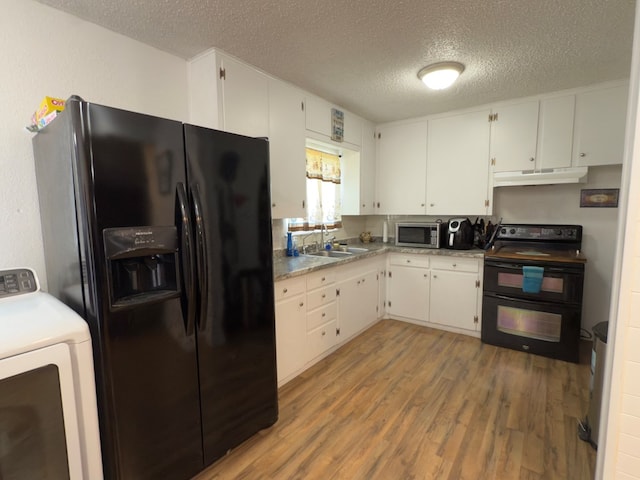 kitchen featuring under cabinet range hood, wood finished floors, washer / clothes dryer, black appliances, and a sink