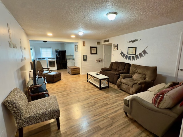 living area with light wood-style flooring, visible vents, and a textured ceiling