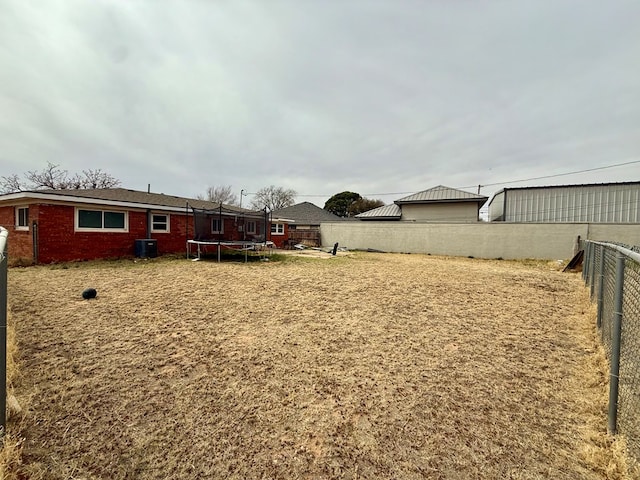 view of yard featuring cooling unit, a trampoline, and fence