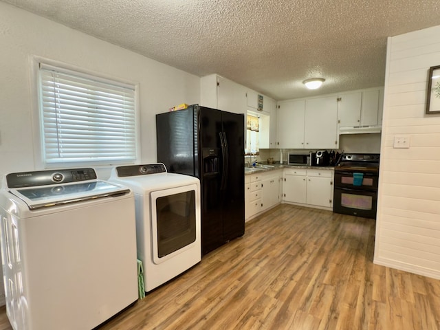 kitchen featuring black appliances, a sink, white cabinetry, light wood finished floors, and washing machine and clothes dryer