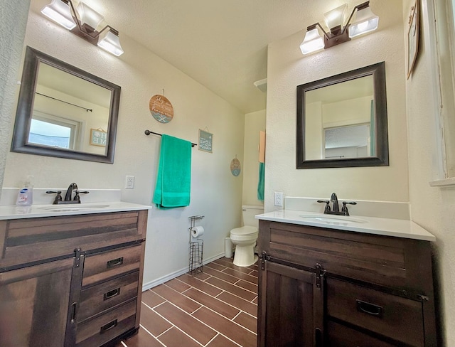 bathroom with a sink, toilet, and two vanities