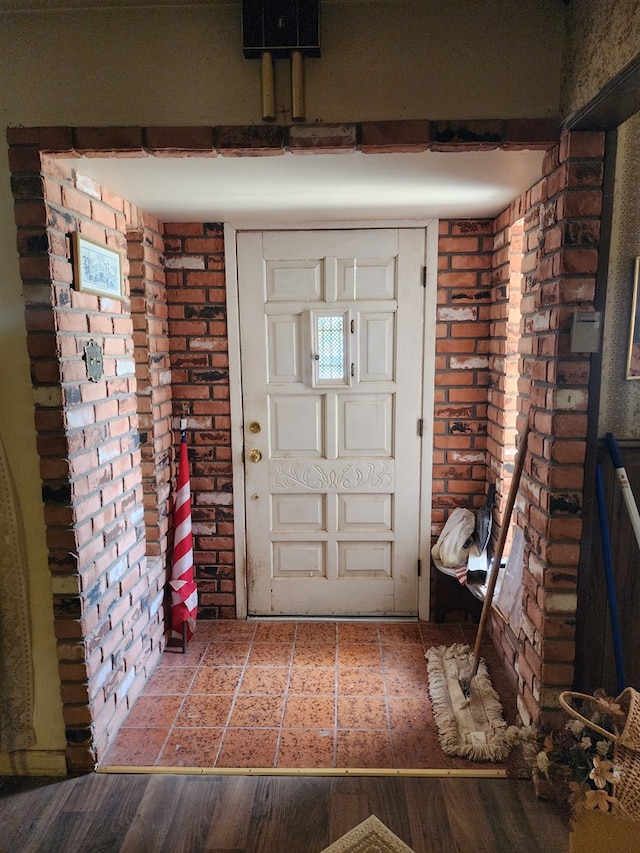 entryway with hardwood / wood-style floors and brick wall