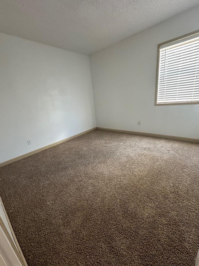 unfurnished room with carpet floors, a textured ceiling, and baseboards