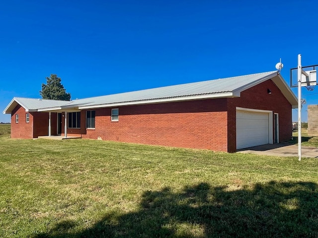 view of side of property featuring brick siding, a lawn, a garage, and metal roof