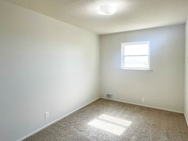 carpeted empty room featuring baseboards, visible vents, and a textured ceiling