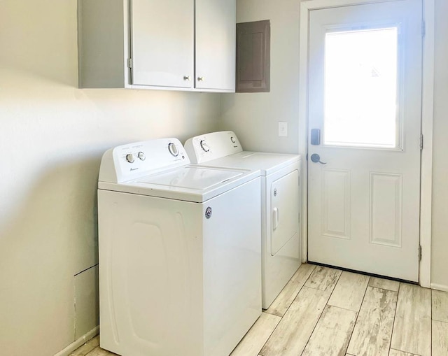 laundry area with cabinet space, light wood-style flooring, and separate washer and dryer