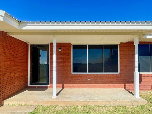 property entrance featuring brick siding and metal roof