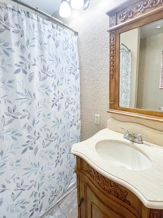 full bath with vanity and a textured wall