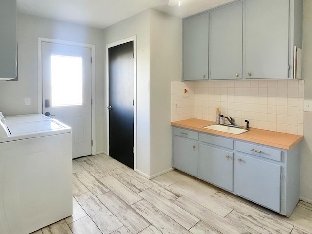 washroom featuring washer and dryer, cabinet space, light wood-style flooring, and a sink