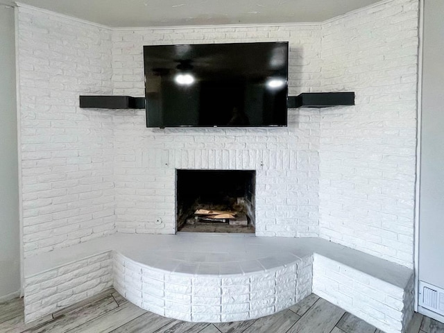 interior details with a brick fireplace, crown molding, and wood finished floors