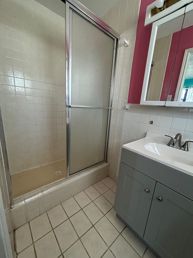 full bathroom featuring tile patterned flooring, vanity, tile walls, and a shower stall
