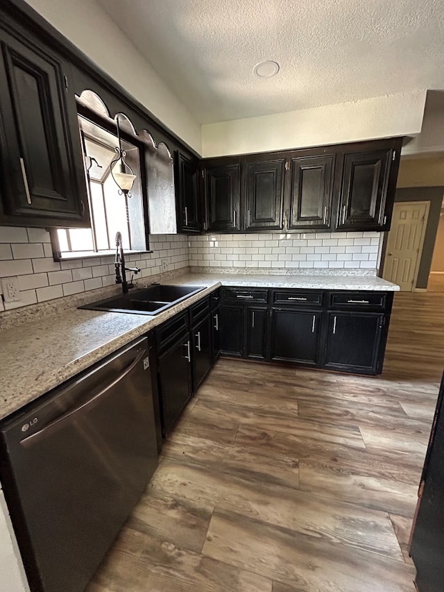 kitchen with dishwashing machine, dark cabinetry, backsplash, and a sink