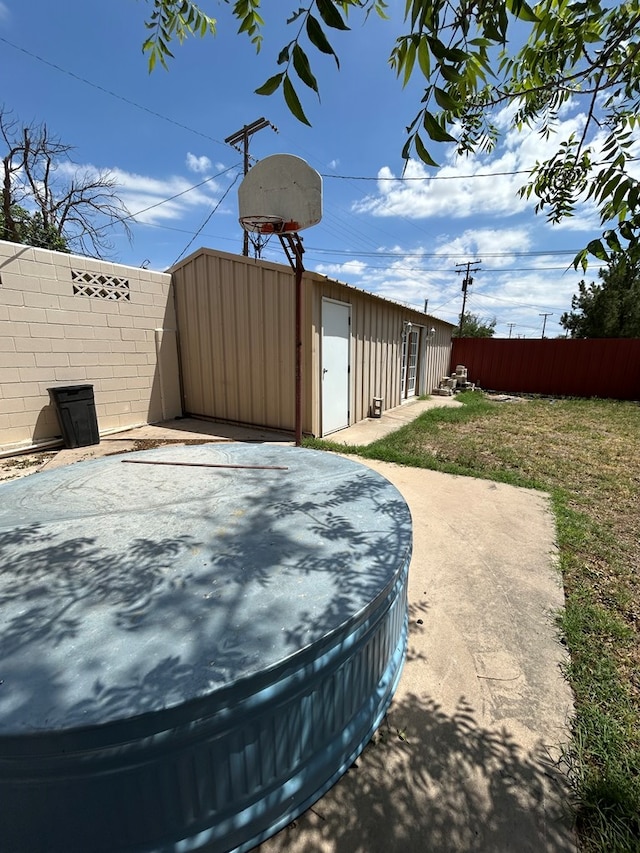 exterior space with fence, an outbuilding, and a jacuzzi