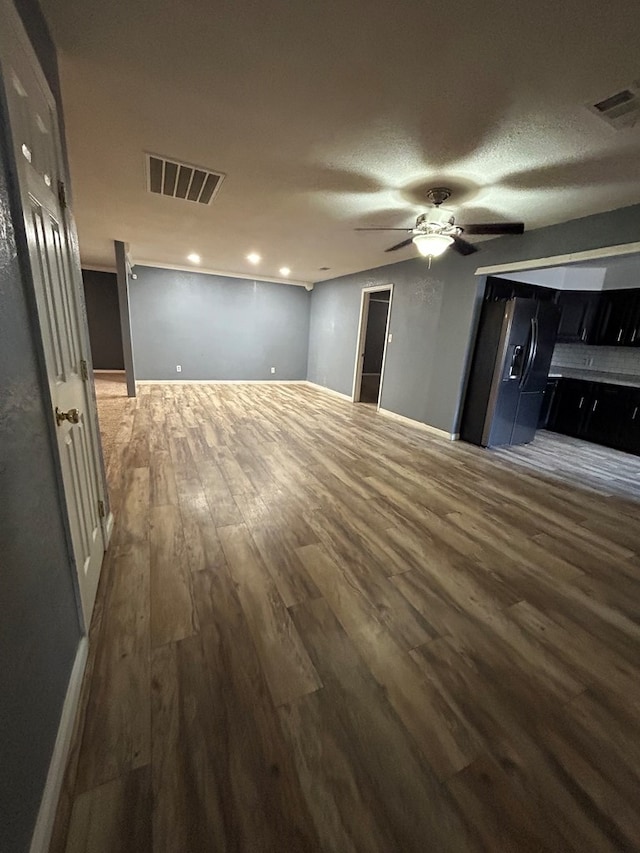 unfurnished room with ceiling fan, wood finished floors, and visible vents