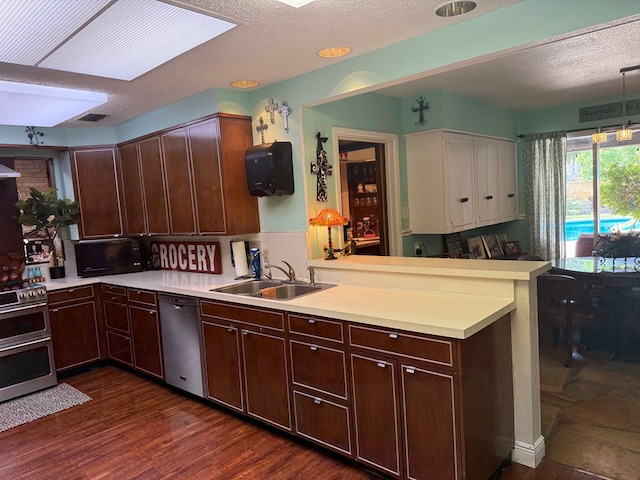 2500 Bainbridge Dr, Odessa, TX 79762 - kitchen with appliances with stainless steel finishes, a peninsula, light countertops, dark brown cabinetry, and a textured ceiling