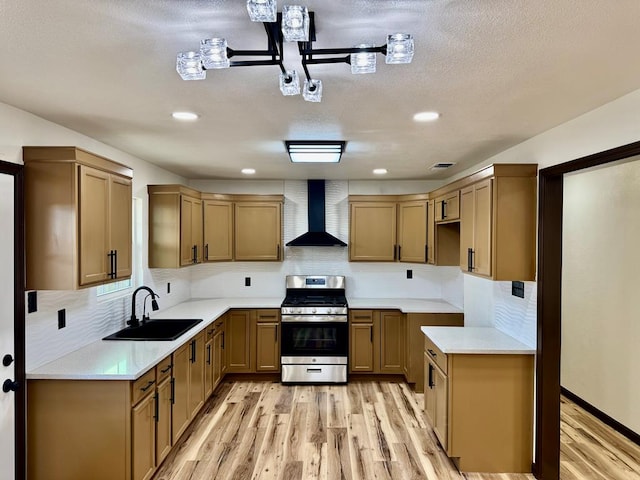 2816 Catalina Dr, Odessa, TX 79764 - kitchen featuring wall chimney range hood, gas range, light wood-style flooring, decorative backsplash, and light countertops