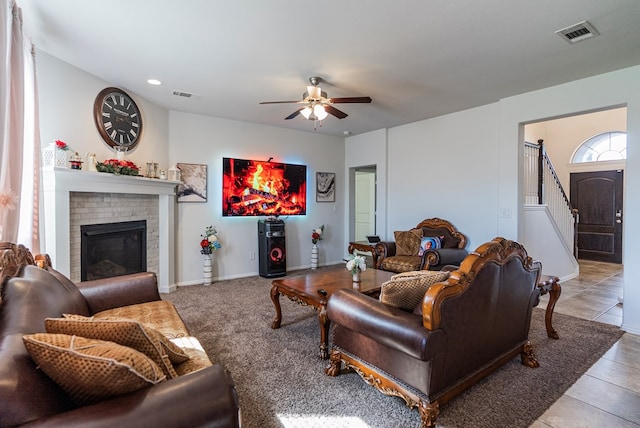 living room featuring light tile patterned floors, a fireplace, and ceiling fan