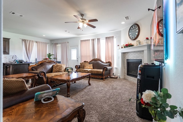 carpeted living room with ceiling fan and a brick fireplace