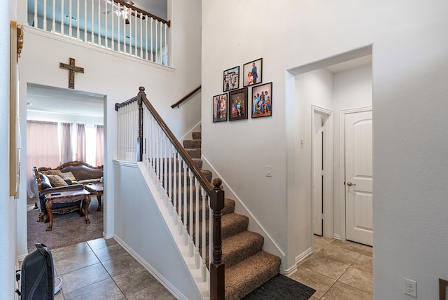 stairway featuring tile patterned floors and a high ceiling