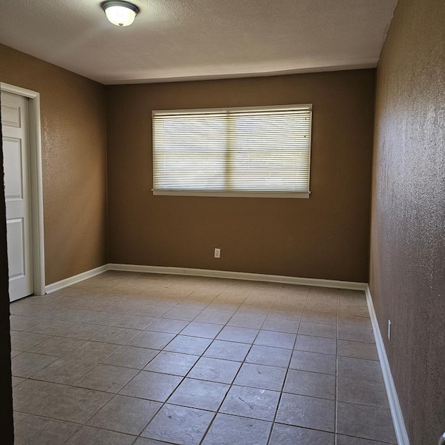 801 W Golf Course Rd, Midland, TX 79701 - spare room featuring light tile patterned floors, a textured wall, baseboards, and a textured ceiling