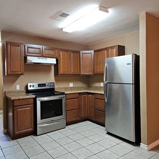 801 W Golf Course Rd, Midland, TX 79701 - kitchen with appliances with stainless steel finishes, under cabinet range hood, brown cabinets, a textured ceiling, and light tile patterned flooring