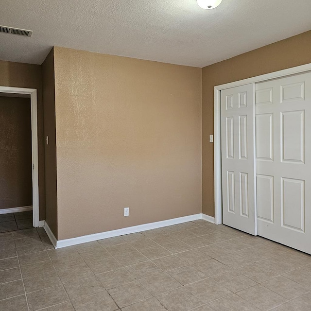 801 W Golf Course Rd, Midland, TX 79701 - unfurnished bedroom featuring light tile patterned floors, a closet, a textured ceiling, and baseboards