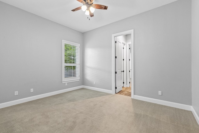 carpeted spare room featuring ceiling fan and baseboards