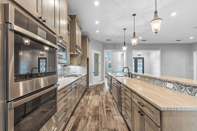 kitchen featuring stainless steel appliances, hardwood / wood-style flooring, backsplash, a sink, and recessed lighting