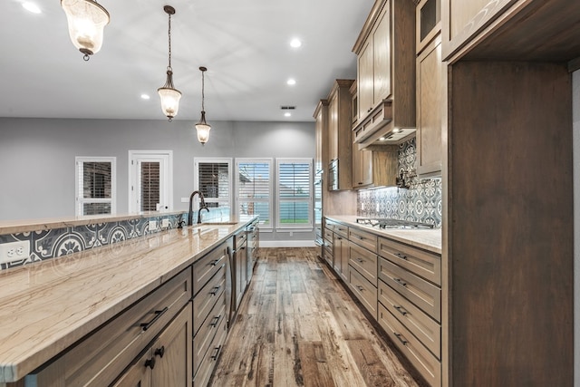 kitchen with a sink, dark wood-style flooring, stainless steel appliances, light stone countertops, and recessed lighting
