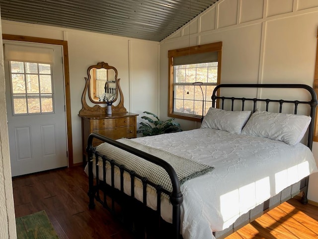 bedroom with lofted ceiling, wooden ceiling, a decorative wall, and wood finished floors