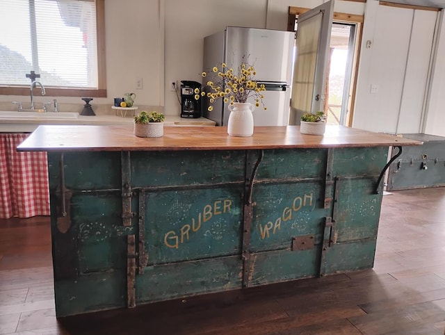 kitchen featuring plenty of natural light, freestanding refrigerator, a sink, and wood finished floors