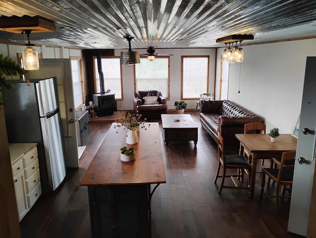 dining room featuring wood ceiling, dark wood-style flooring, and a wood stove