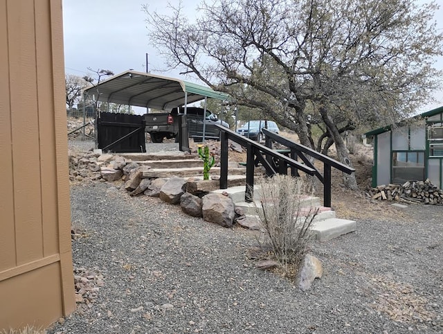 view of yard featuring a carport, fence, and driveway