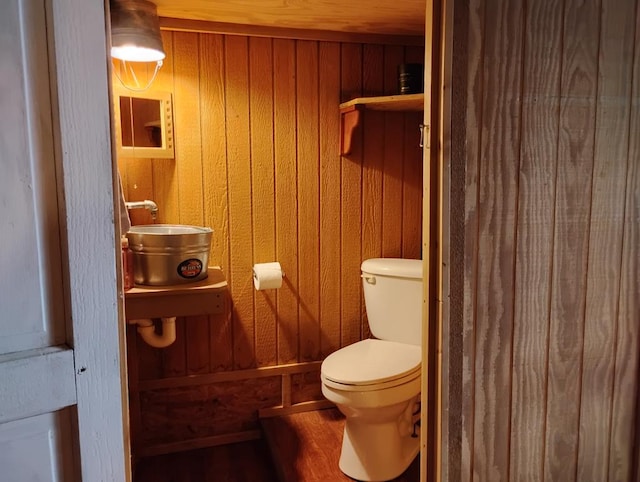 bathroom featuring wood walls and toilet