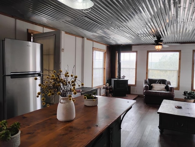 dining space featuring wood ceiling, hardwood / wood-style floors, a wood stove, and a ceiling fan