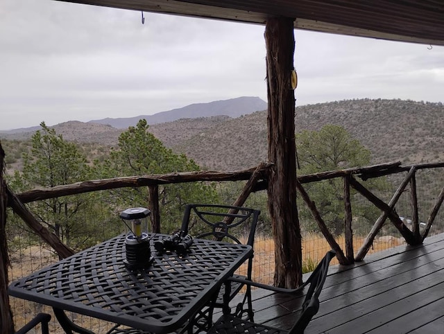 balcony with a mountain view, a view of trees, and outdoor dining space