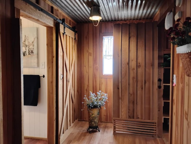 interior space with wood finished floors, wood walls, and a barn door