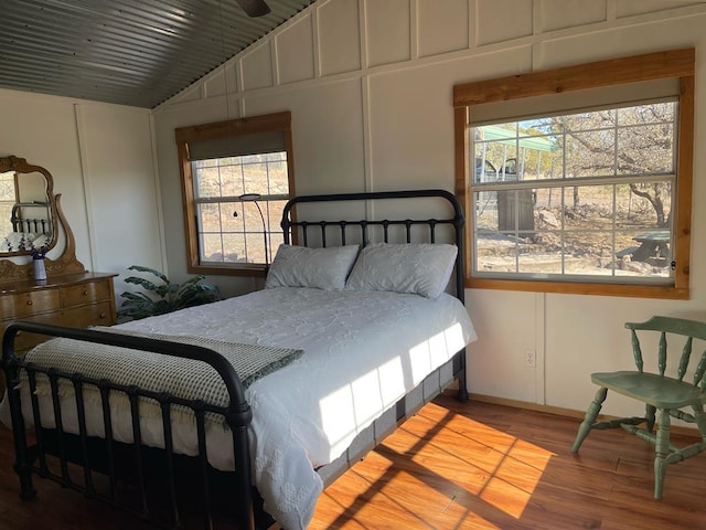 bedroom featuring multiple windows, wood finished floors, and a decorative wall