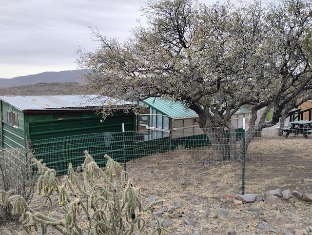 view of yard featuring fence, exterior structure, a mountain view, and an outbuilding