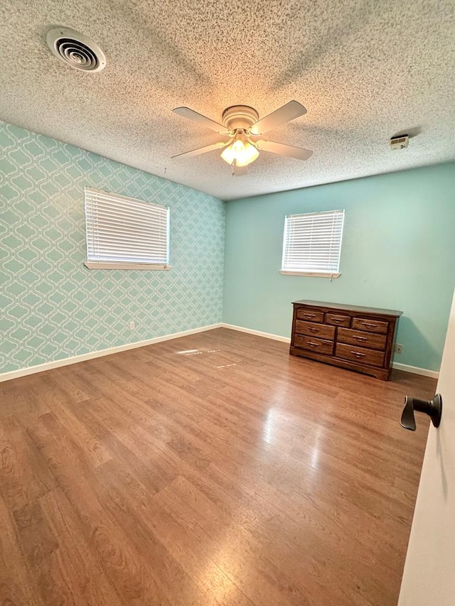 2003 N Enfield Rd, Alpine, TX 79830 - empty room with baseboards, wood finished floors, wallpapered walls, and a ceiling fan