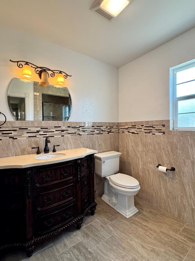 2003 N Enfield Rd, Alpine, TX 79830 - bathroom featuring tile walls, toilet, vanity, wainscoting, and tile patterned floors