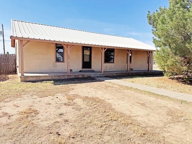 1106 W Eagle Pass, Alpine, TX 79830 - view of front facade with fence, stucco siding, metal roof, and covered porch