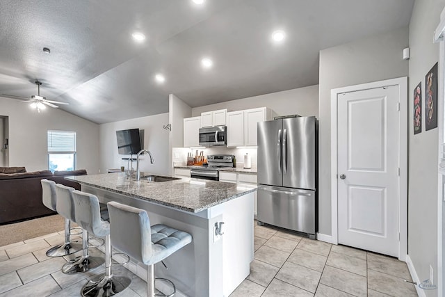 1320 E 94th St, Odessa, TX 79765 - kitchen with appliances with stainless steel finishes, white cabinetry, a kitchen bar, light stone countertops, and lofted ceiling