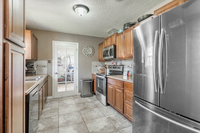1714 E 53rd St, Odessa, TX 79762 - kitchen with stainless steel appliances, light countertops, a textured ceiling, and brown cabinetry